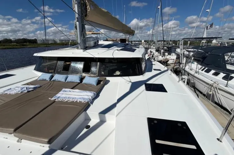 Slide: The Image of 2018 Fountaine Pajot Saona 47 catamaran with sunbathing area, docked under blue skies. - 9
