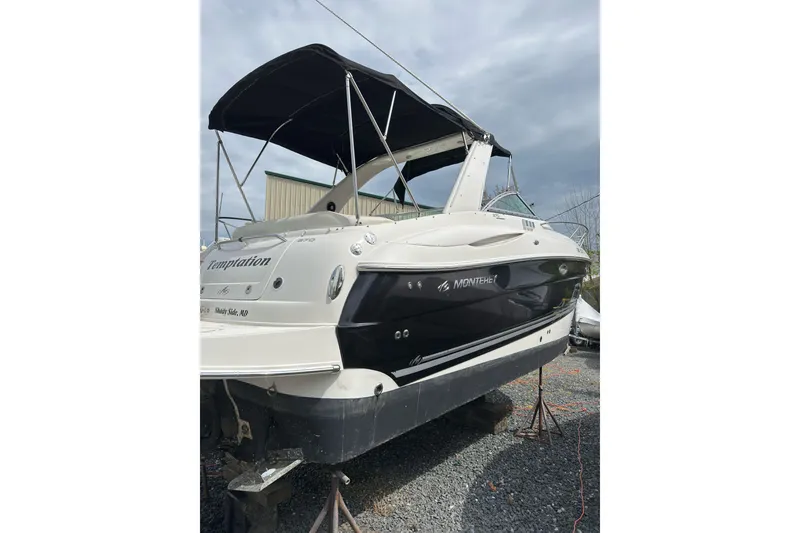 The Image of 2007 Monterey 270 Cruiser boat with black canopy, docked on gravel. - 1