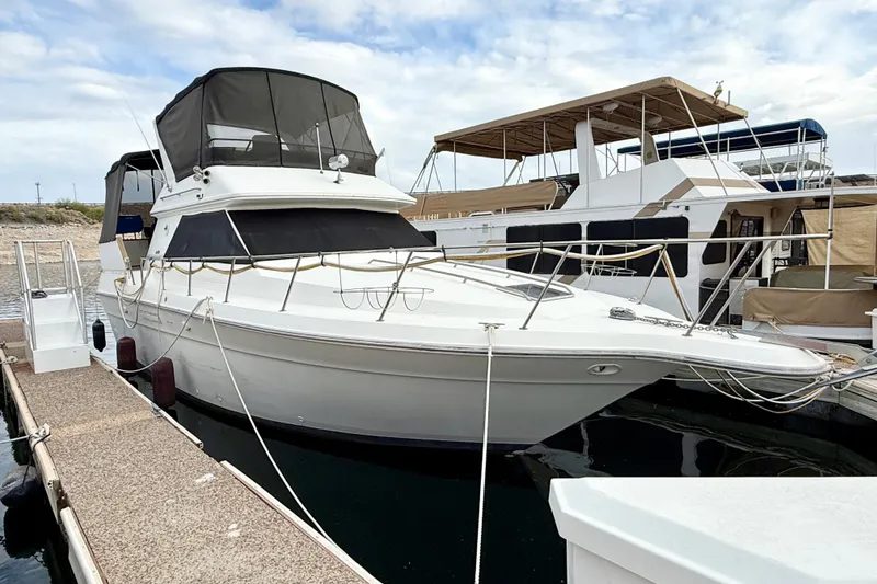 The Image of 1989 Sea Ray 380 Aft Cabin yacht docked at marina under cloudy sky. - 0