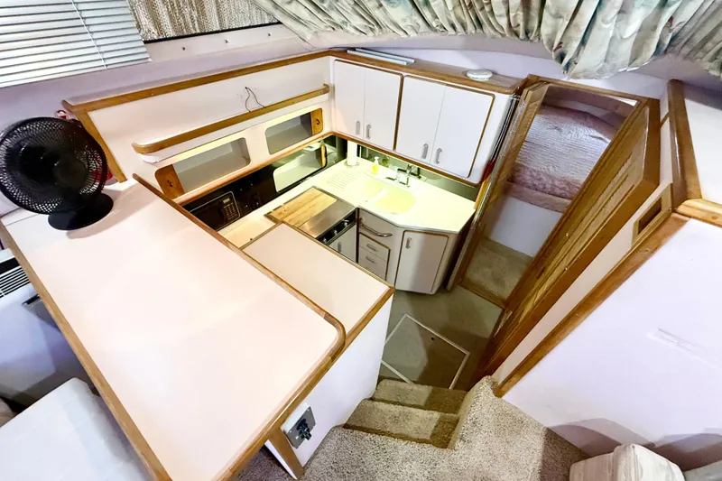 Slide: The Image of 1989 Sea Ray 380 Aft Cabin yacht interior with compact kitchen and cozy sleeping area. - 12