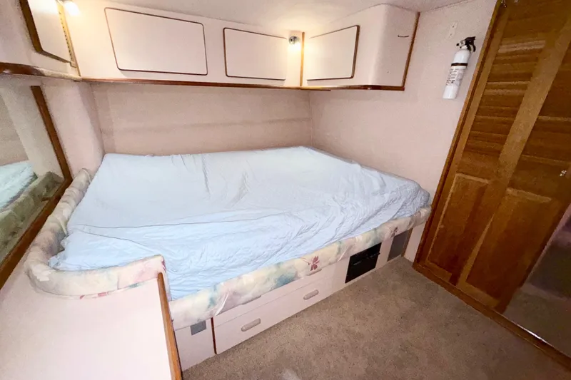 Slide: The Image of 1989 Sea Ray 380 Aft Cabin bedroom with bed, storage, and wooden cabinetry. - 25