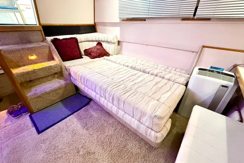Slide: The Image of 1989 Sea Ray 380 Aft Cabin interior with cozy seating, carpeted stairs, and ambient lighting. - 28