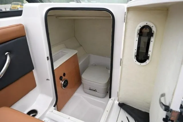 Slide: The Image of 2017 Glastron GT 245 boat interior with compact cabin and portable toilet. - 15