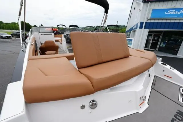 Slide: The Image of 2017 Glastron GT 245 boat with tan seating, docked near a dealership. - 17
