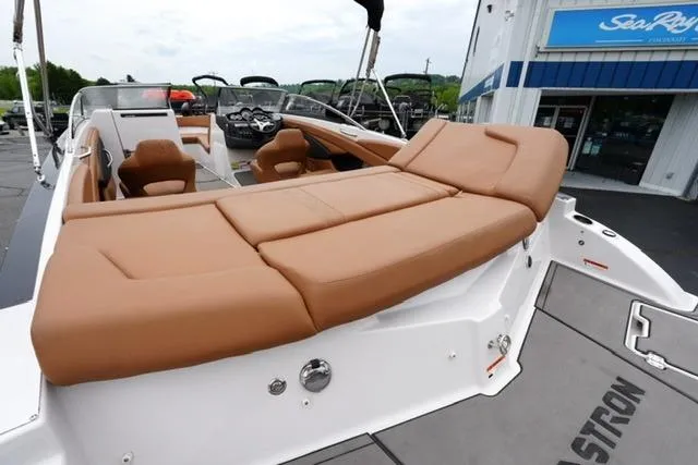 Slide: The Image of 2017 Glastron GT 245 boat with tan seating, displayed at a dealership. - 18