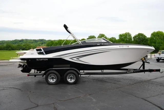 Slide: The Image of 2017 Glastron GT 245 boat on trailer, parked outdoors with green landscape background. - 4