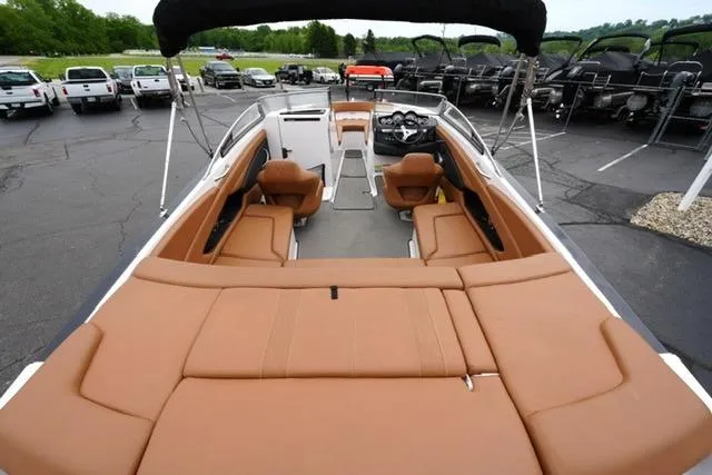 Slide: The Image of 2017 Glastron GT 245 boat with tan seating, parked in a lot with other vehicles. - 8