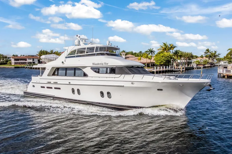 Slide: The Image of 2009 Cheoy Lee 78 yacht cruising near luxury waterfront homes under a clear blue sky. - 2