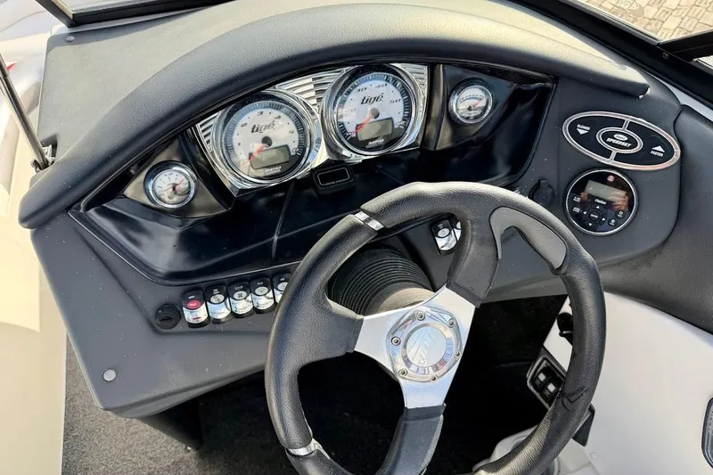 Slide: The Image of Steering wheel and dashboard of a 2012 Tigé R20 boat, featuring gauges and controls. - 16
