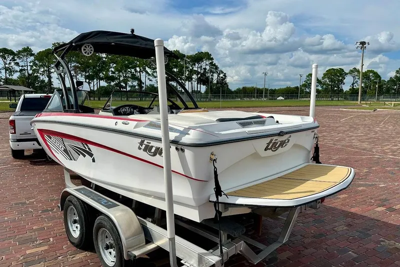 Slide: The Image of 2012 Tigé R20 boat on trailer, parked on brick pavement under a cloudy sky. - 2