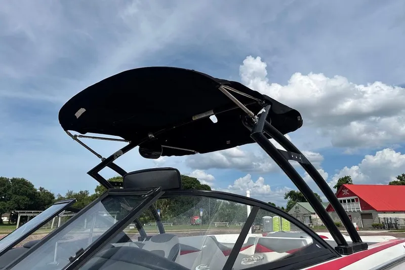 Slide: The Image of 2012 Tigé R20 boat with black bimini top against a cloudy sky backdrop. - 27