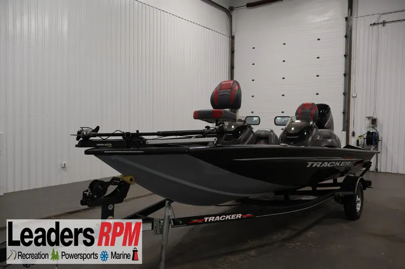 The Image of 2022 Tracker Pro Team 175 TXW boat in showroom, featuring dual seats and trailer. - 1