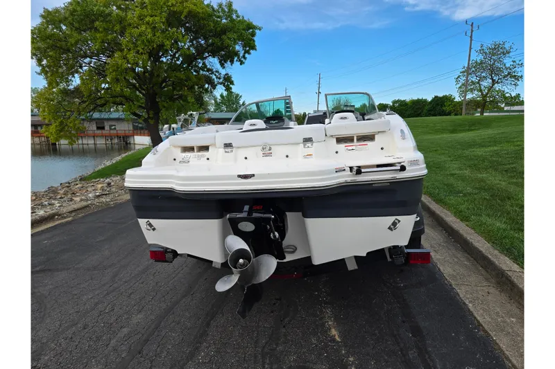 Slide: The Image of 2016 Chaparral 19 H2O Sport boat, rear view, parked near a lake with lush greenery. - 2