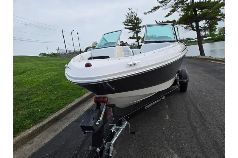 Slide: The Image of 2016 Chaparral 19 H2O Sport boat on trailer, parked near a lake. - 6