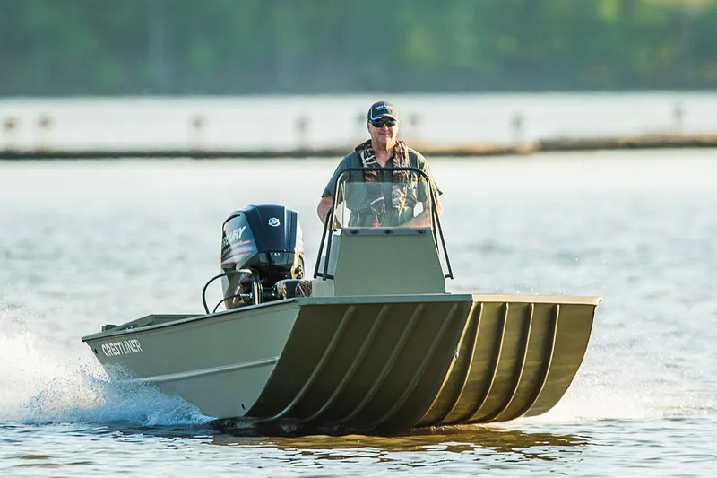 The Image of Manufacturer Provided Image: 2026 Crestliner 1660 Retriever FCC boat cruising on a lake with a person steering. - 0