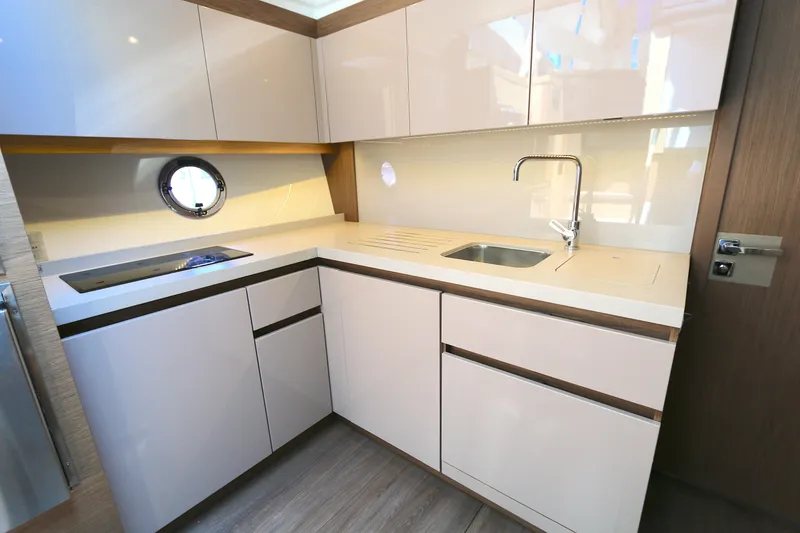 Slide: The Image of Modern kitchen interior of 2019 Beneteau Gran Turismo 50 yacht, featuring sleek cabinetry and porthole window. - 5