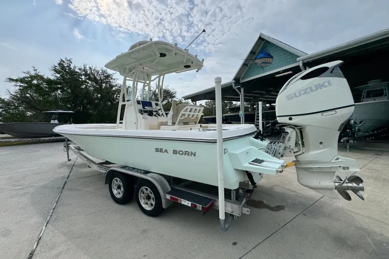 Slide: The Image of 2019 Sea Born FX25 Bay boat on trailer with Suzuki outboard motor, parked outdoors. - 16
