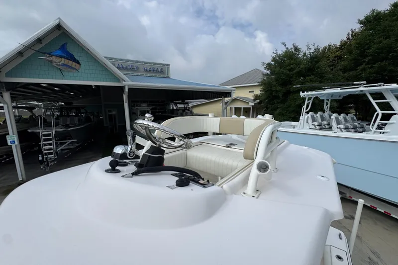 Slide: The Image of 2019 Sea Born FX25 Bay boat at a marina, showcasing helm and seating area. - 24