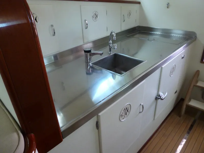 Slide: The Image of 1949 Rybovich Sport Fish boat kitchen with stainless steel sink and wooden cabinetry. - 30