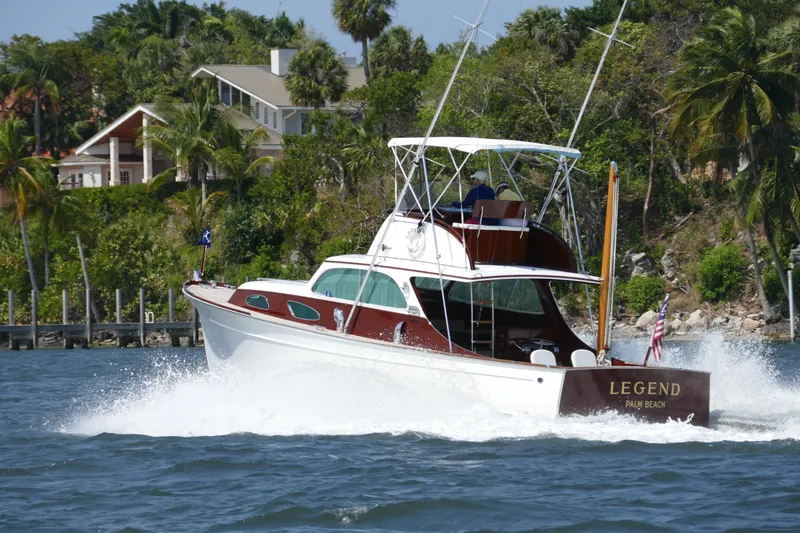 Slide: The Image of 1949 Rybovich Sport Fish boat cruising on water near lush shoreline. - 4