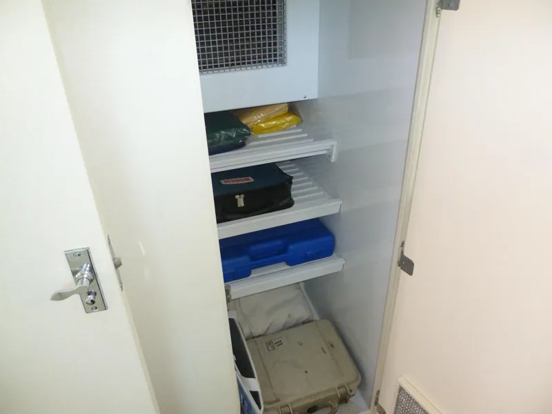 Slide: The Image of Storage shelves inside a 1949 Rybovich Sport Fish boat, holding various equipment and cases. - 40