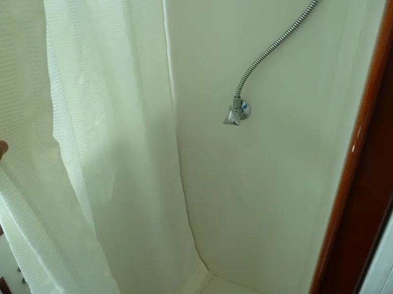 Slide: The Image of Shower area inside a 1949 Rybovich Sport Fish boat, featuring a curtain and hose. - 49