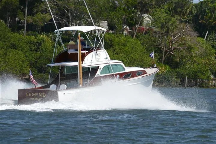 Slide: The Image of 1949 Rybovich Sport Fish boat cruising on water, surrounded by lush greenery. - 5