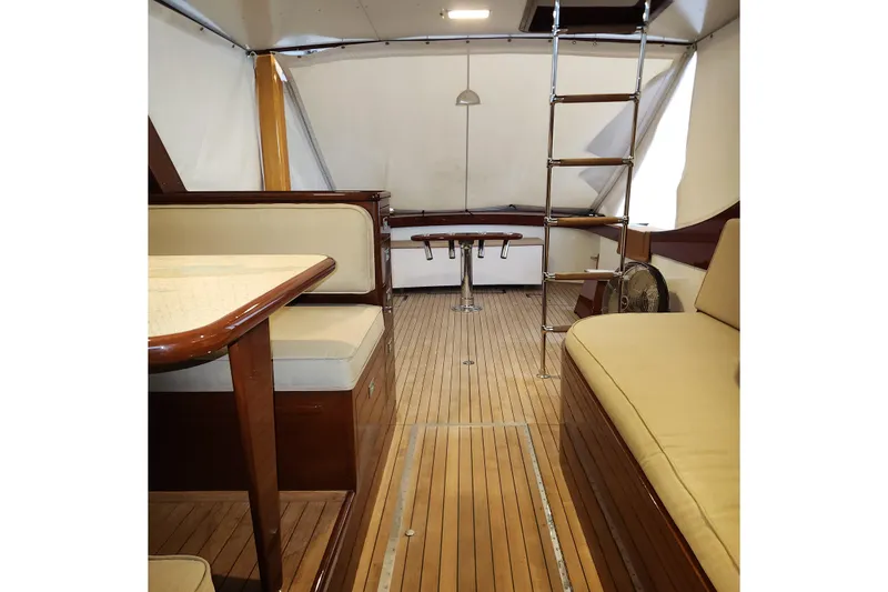 Slide: The Image of 1949 Rybovich Sport Fish interior with wooden flooring and beige seating. - 57