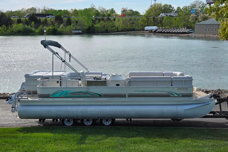 The Image of 1999 Bennington 2275LX pontoon boat on trailer by a scenic lake. - 0