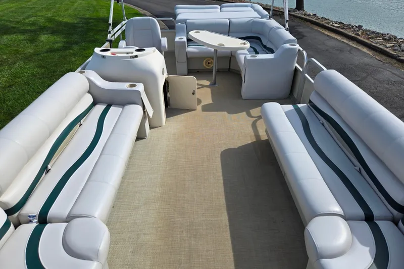 Slide: The Image of 1999 Bennington 2275LX pontoon boat interior with spacious seating and table by the water. - 10
