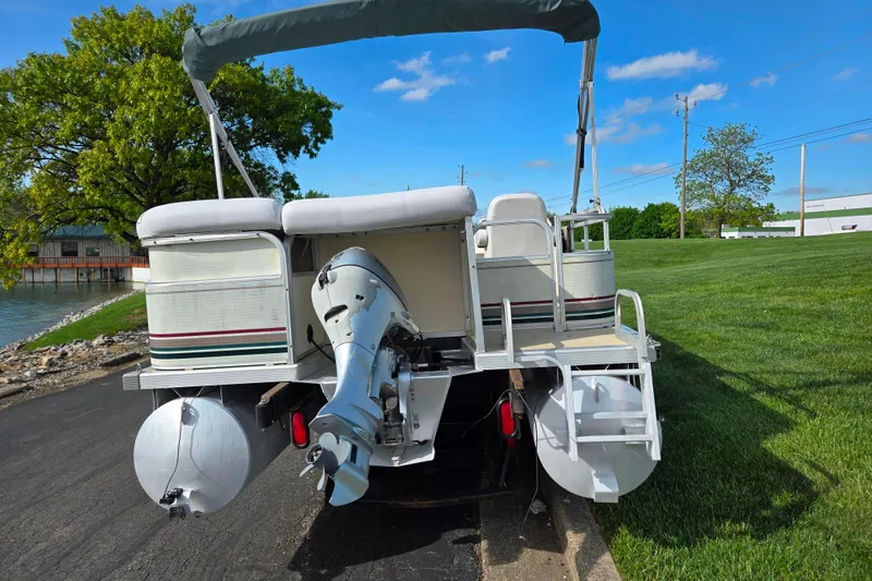 Slide: The Image of 1999 Bennington 2275LX pontoon boat with outboard motor, parked near a lake on a sunny day. - 2