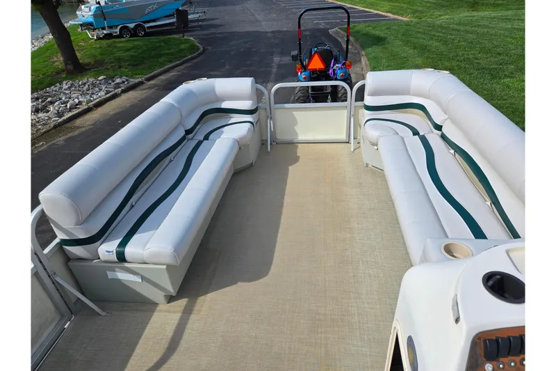 Slide: The Image of 1999 Bennington 2275LX pontoon boat interior with white and green seating, parked near water. - 22