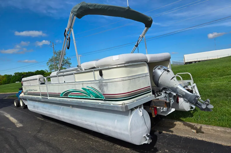 Slide: The Image of 1999 Bennington 2275LX pontoon boat with outboard motor on a trailer, parked on pavement. - 3