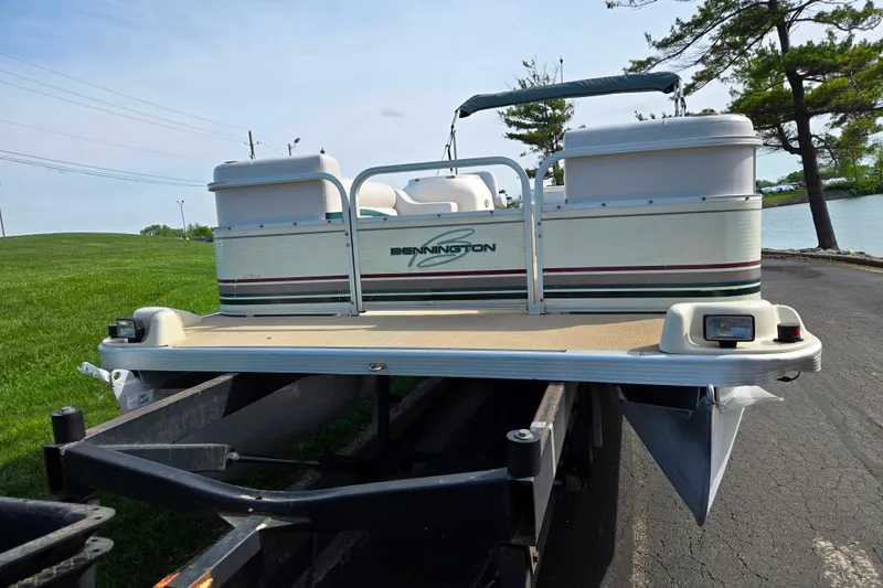 Slide: The Image of 1999 Bennington 2275LX pontoon boat on trailer by a lake. - 6