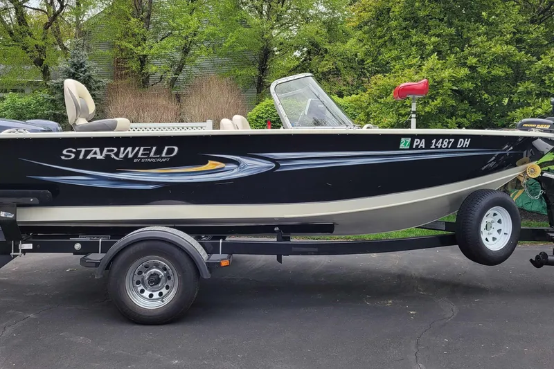 Slide: The Image of Starweld 1800 boat on trailer, 2011 model, parked on driveway with lush greenery. - 11