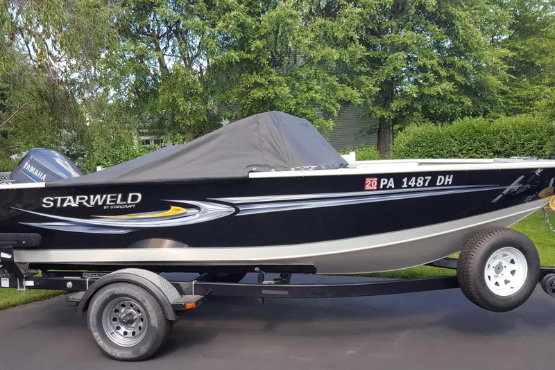 Slide: The Image of Starweld 1800 boat on trailer, covered, with Yamaha motor, parked outdoors. - 19