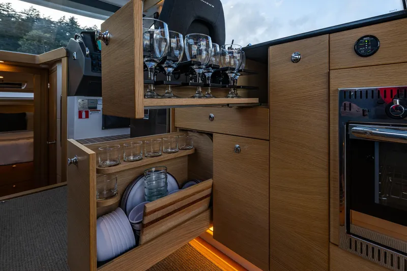 Slide: The Image of Modern kitchen interior of 2022 Nimbus 365 Coupe with wooden cabinetry and glassware storage. - 12