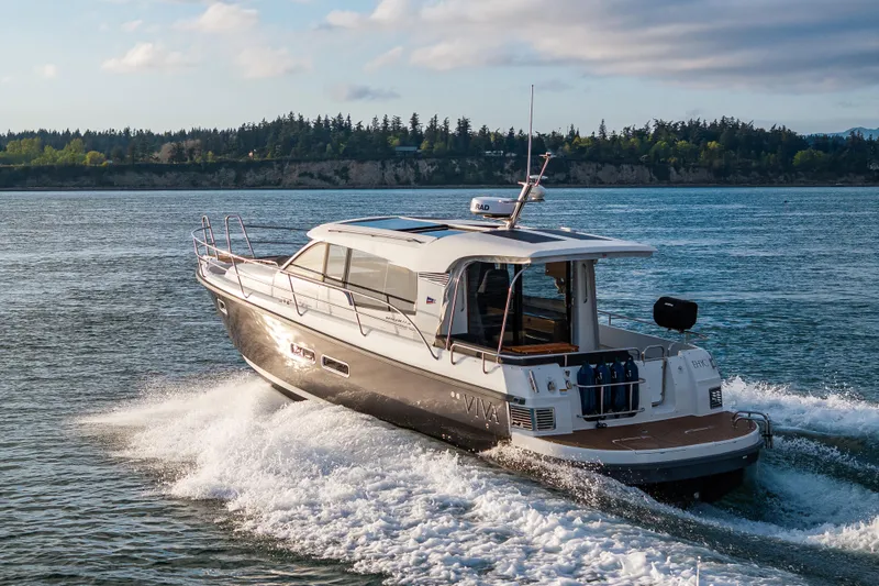 Slide: The Image of 2022 Nimbus 365 Coupe cruising on a scenic waterway with lush green shoreline. - 19