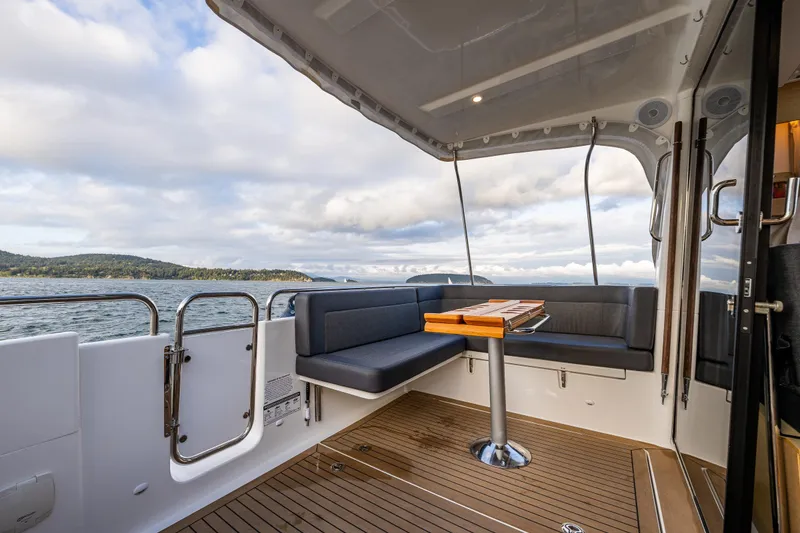 Slide: The Image of Nimbus 365 Coupe 2022 boat interior with seating and table, overlooking scenic water view. - 23