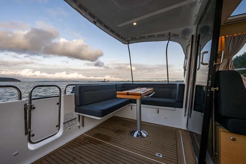 Slide: The Image of 2022 Nimbus 365 Coupe boat interior with seating, table, and ocean view. - 25