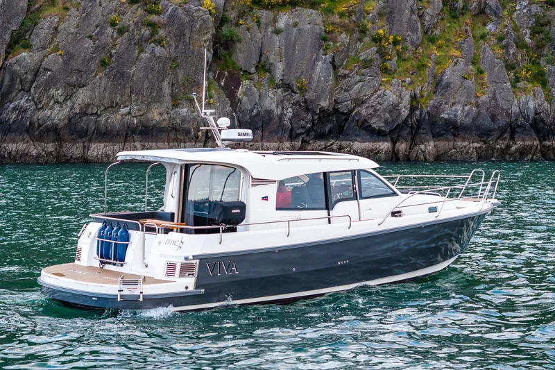 Slide: The Image of 2022 Nimbus 365 Coupe boat cruising near rocky shoreline. - 27