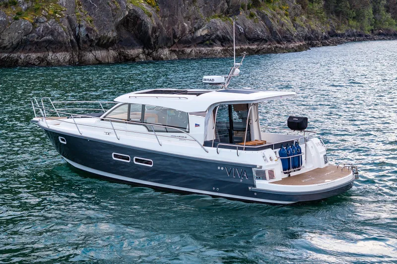 Slide: The Image of 2022 Nimbus 365 Coupe boat cruising on scenic water near rocky shoreline. - 31