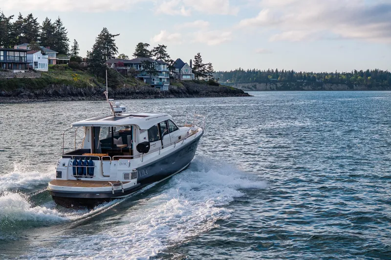 Slide: The Image of 2022 Nimbus 365 Coupe cruising near coastal homes on a sunny day. - 32