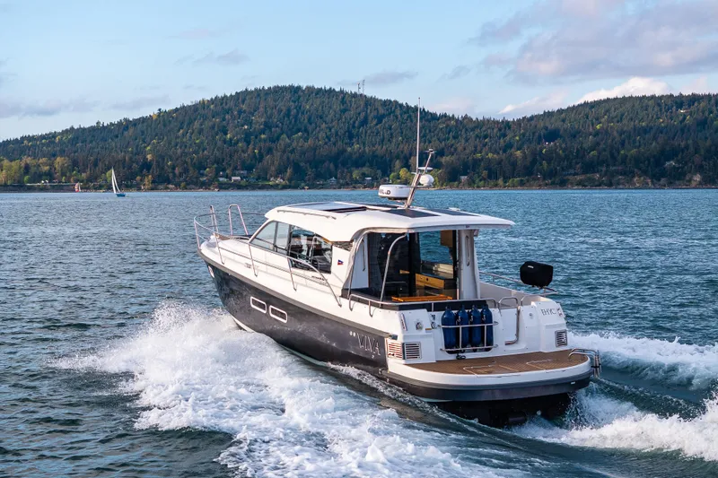 Slide: The Image of Nimbus 365 Coupe 2022 cruising on a scenic lake with forested hills in the background. - 33