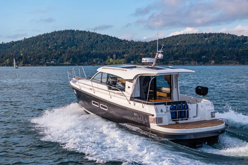 Slide: The Image of 2022 Nimbus 365 Coupe cruising on a scenic lake with forested hills in the background. - 34