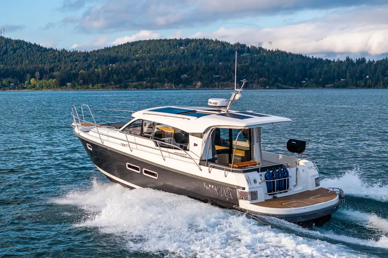 Slide: The Image of 2022 Nimbus 365 Coupe cruising on a scenic lake with forested hills in the background. - 35