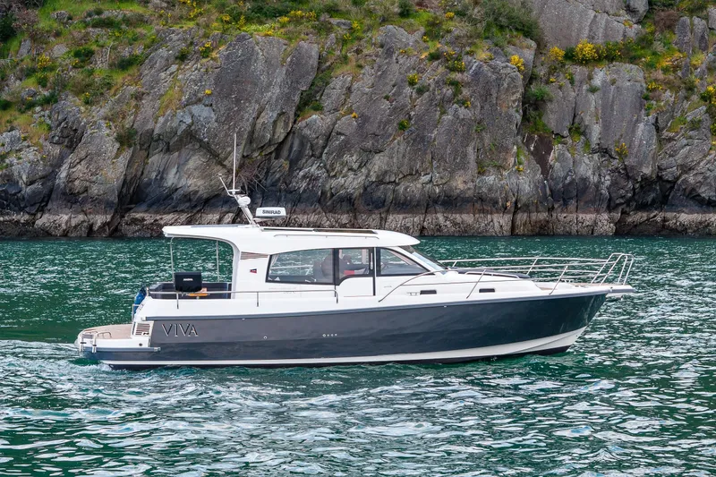 Slide: The Image of Nimbus 365 Coupe 2022 boat cruising near rocky shoreline. - 39