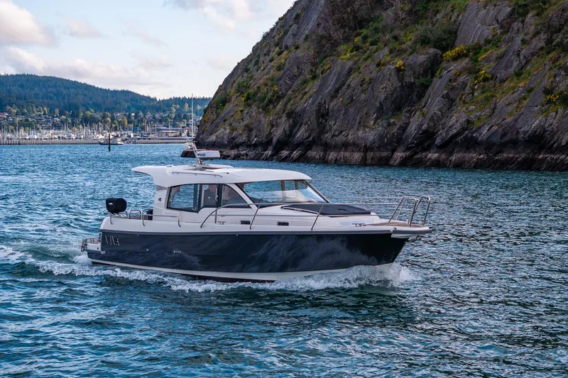 Slide: The Image of 2022 Nimbus 365 Coupe cruising near rocky coastline with marina in background. - 42