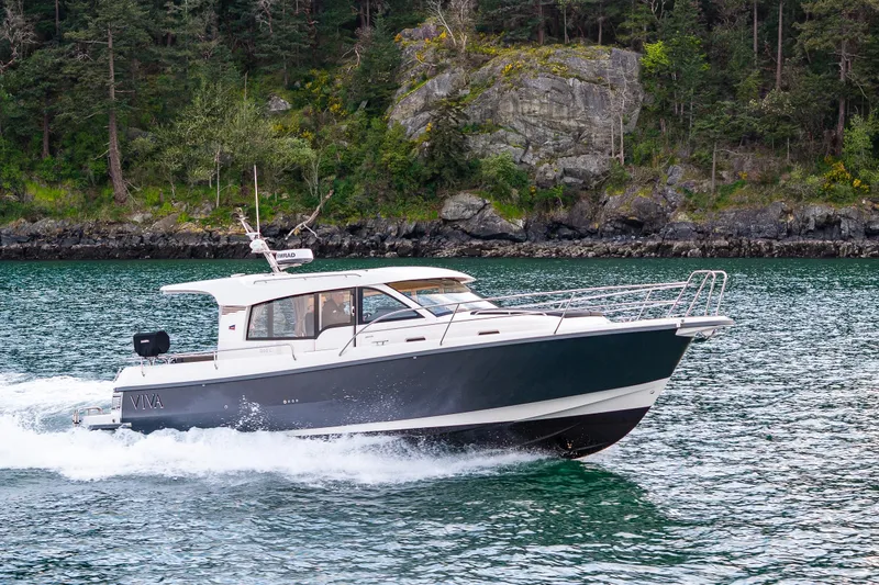 Slide: The Image of 2022 Nimbus 365 Coupe cruising on a scenic lake with forested shoreline. - 45