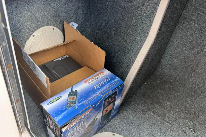 Slide: The Image of Cardboard box with marine radio inside a 2006 Grady-White Tournament 205 boat compartment. - 24